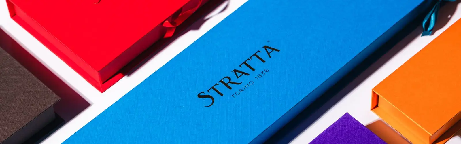 Le confezioni Stratta in rosso, blu e arancio, coi nomi in oro