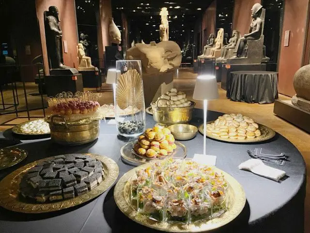 Un evento aziendale fra le statue egizie: tavoli rotondi coi vassoi di pasticceria