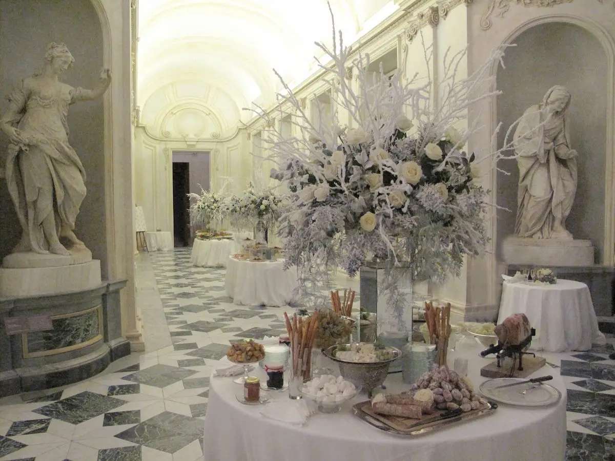 Un buffet di Natale allestito da Stratta in una galleria di statue, coi fiori bianchi