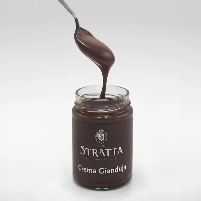 Un vasetto di crema gianduja Stratta col cucchiaino che cola