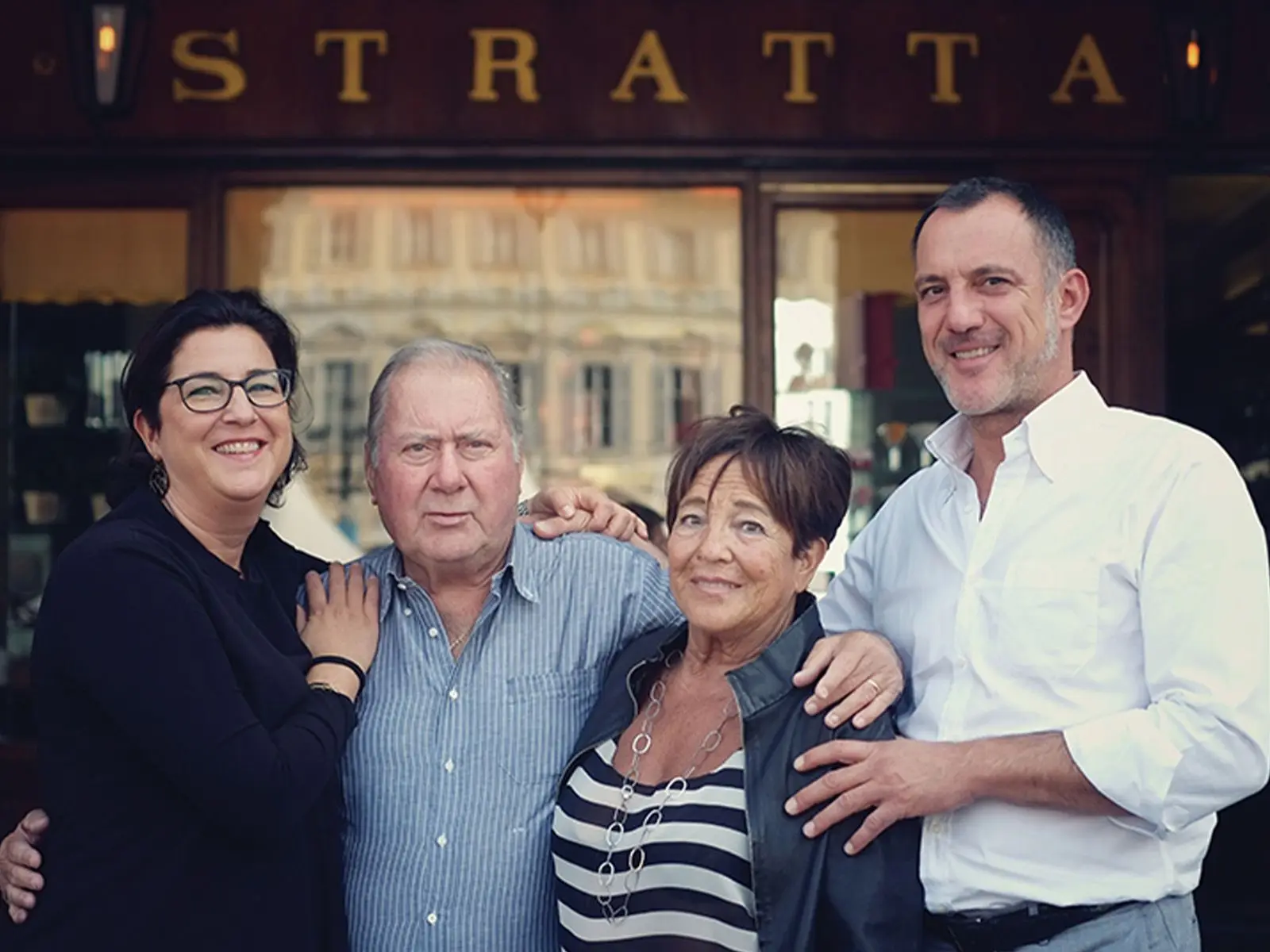 La famiglia Stratta davanti al negozio, sotto l'insegna dorata