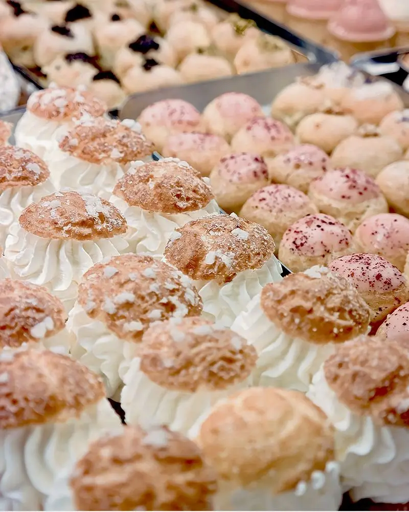 Il bancone della pasticceria mignon: file di bignè alla crema