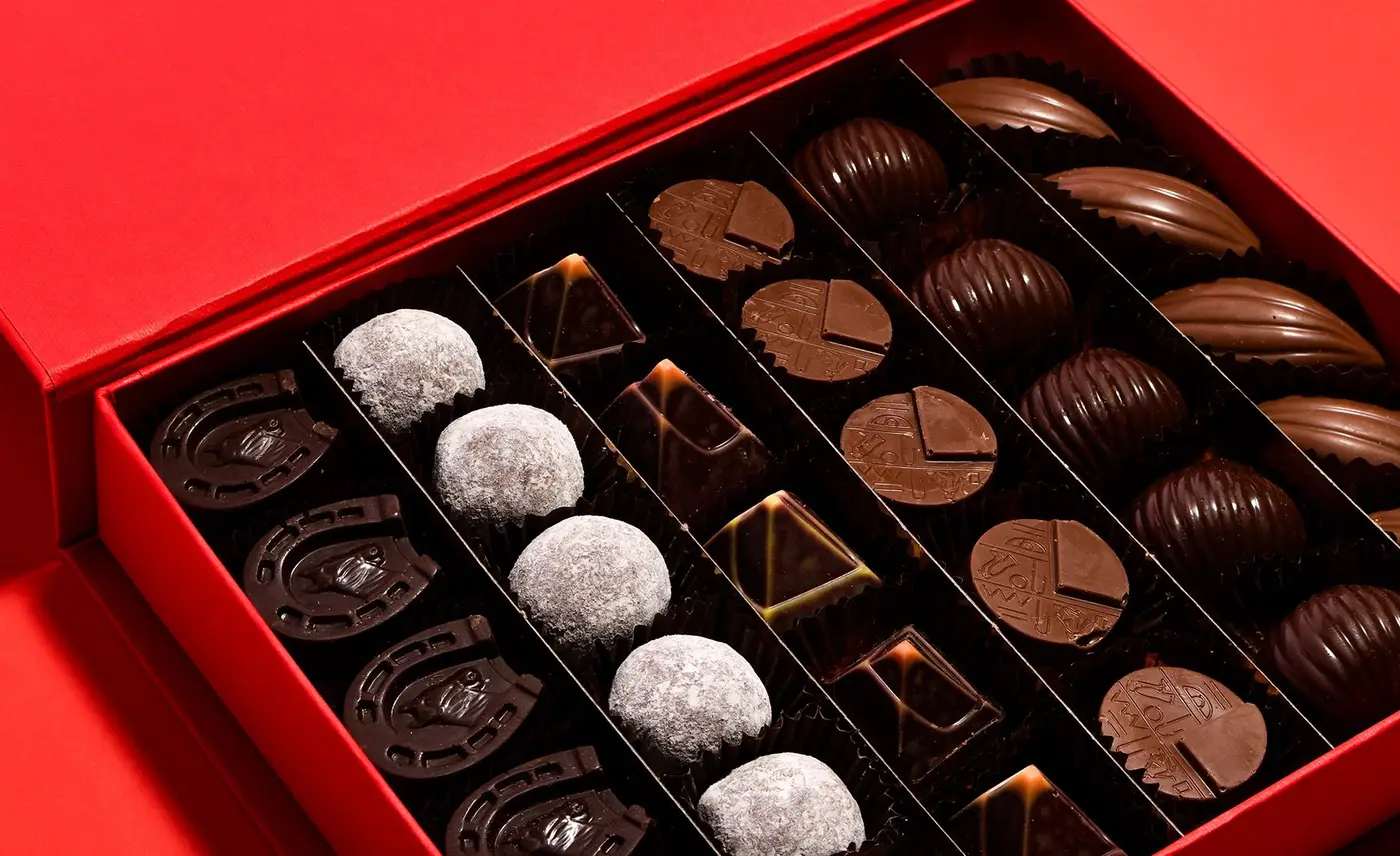 Una scatola rossa Stratta aperta: praline di cioccolato al latte, fondente e bianche nei loro scomparti